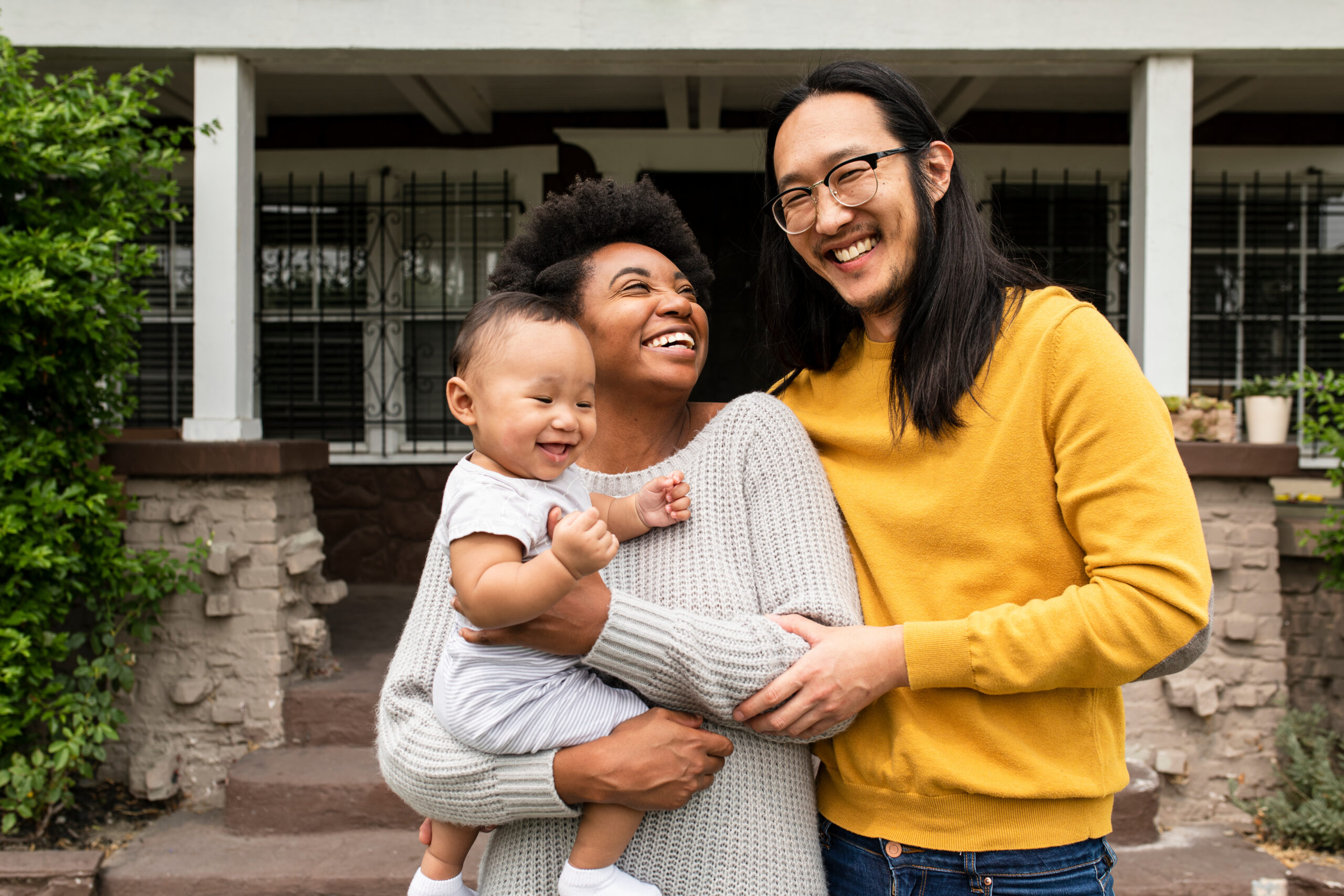 Happy multiethnic family standing in front of the house during c